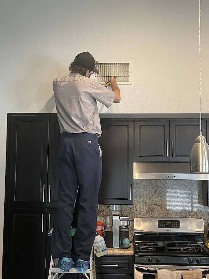 Technician inspecting an air vent during HVAC service in Blair